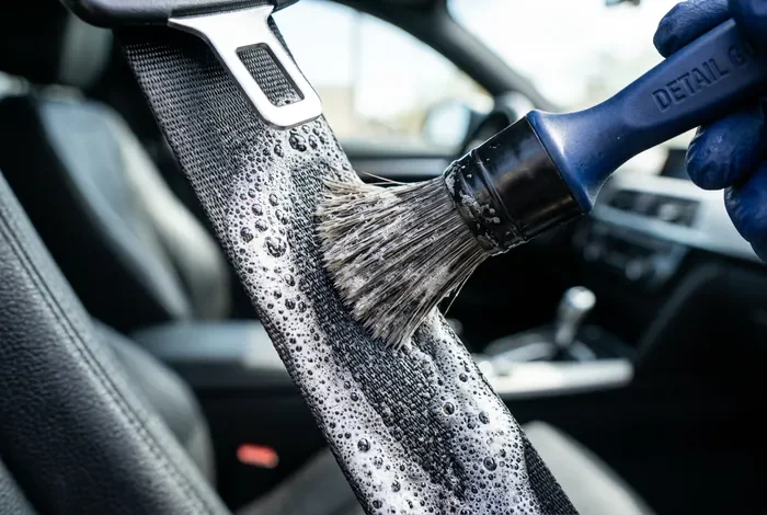 Brosse de detailing nettoyant une ceinture de sécurité avec de la mousse active