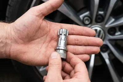 Gros plan sur une douille antivol de jante Volkswagen dans une main